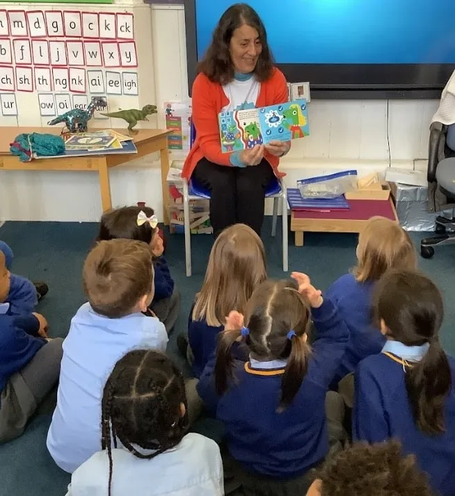 Heather Maisner showing a class of young children a page from Dinosaur Douglas and the Yucky Mucky Fingers