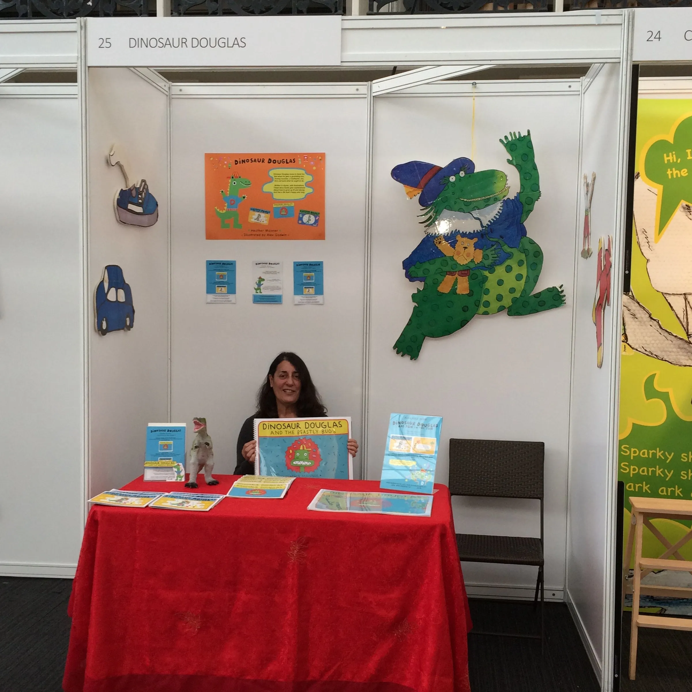 Heather Maisner holding the Big Book edition of Dinosaur Douglas and the Beastly Bugs at an exhibition stand