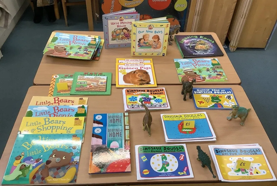 Heather Maisner's books laid out on tables for a school visit, with toy dinosaurs between them